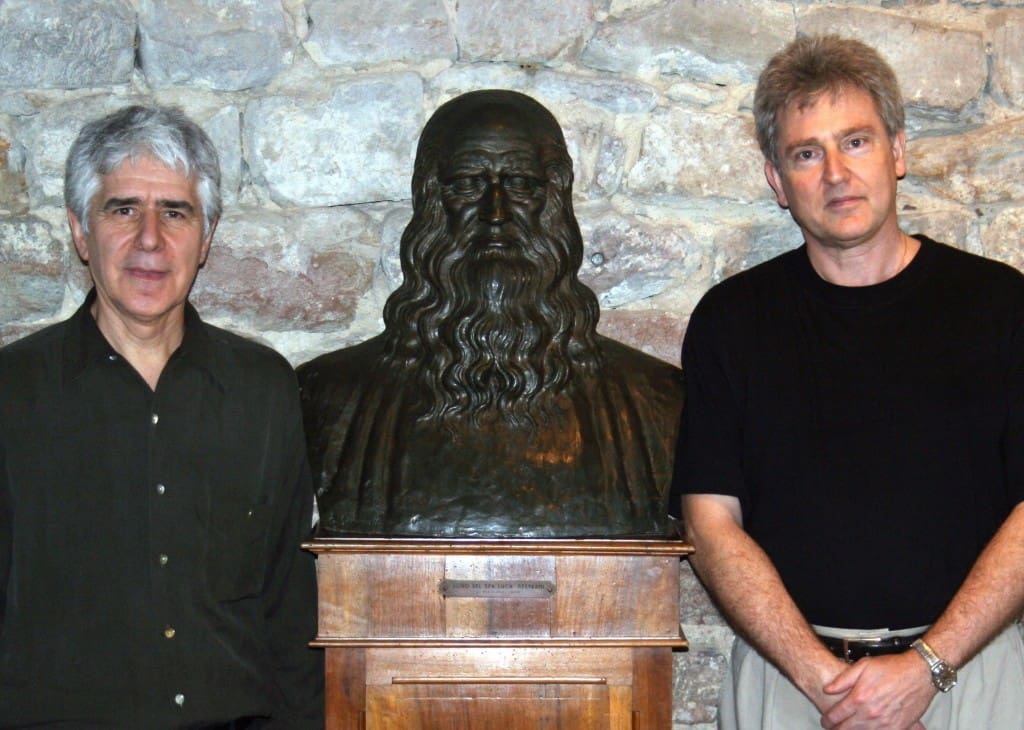 Two men standing next to a bust of a man.